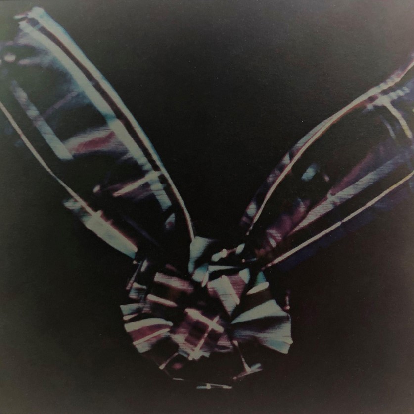 Photograph of a green, red and blue tartan ribbon against a black backdrop.
