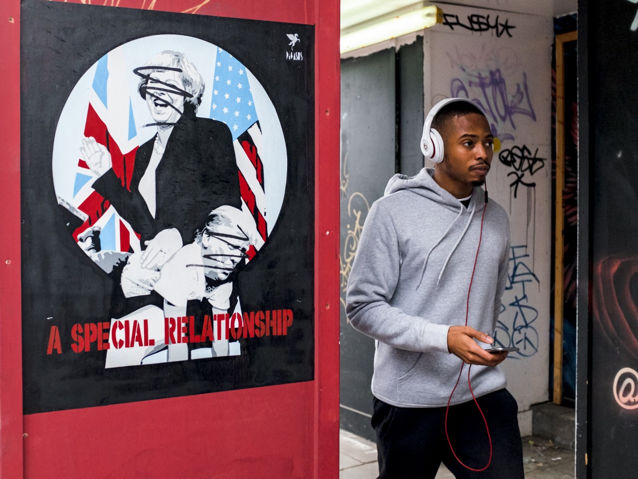 Young man with earphone passing a political poster