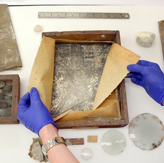 Two gloved hands show materials from James Watt's workshop.