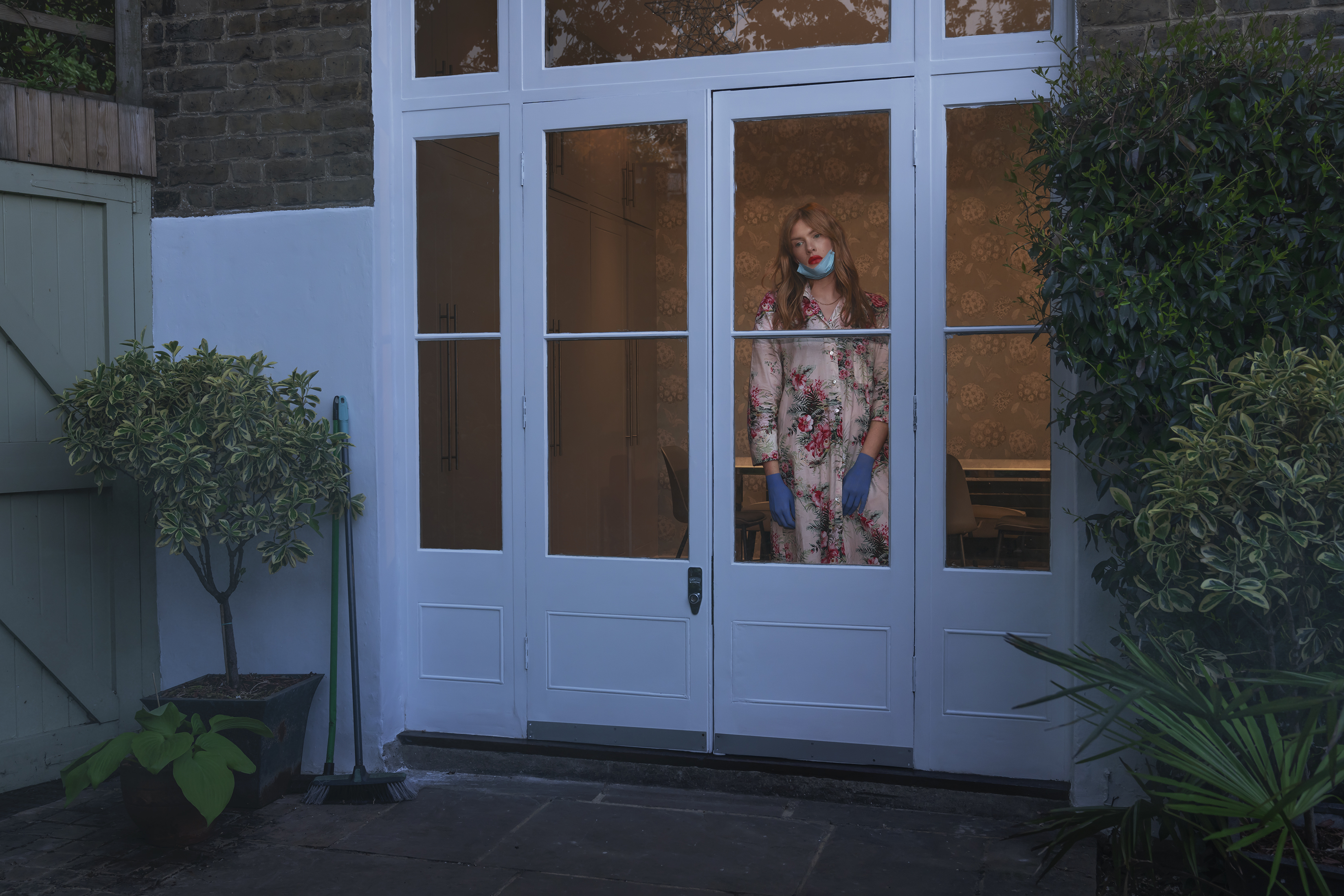 Bethan looks out on to her garden in floral dress and face mask